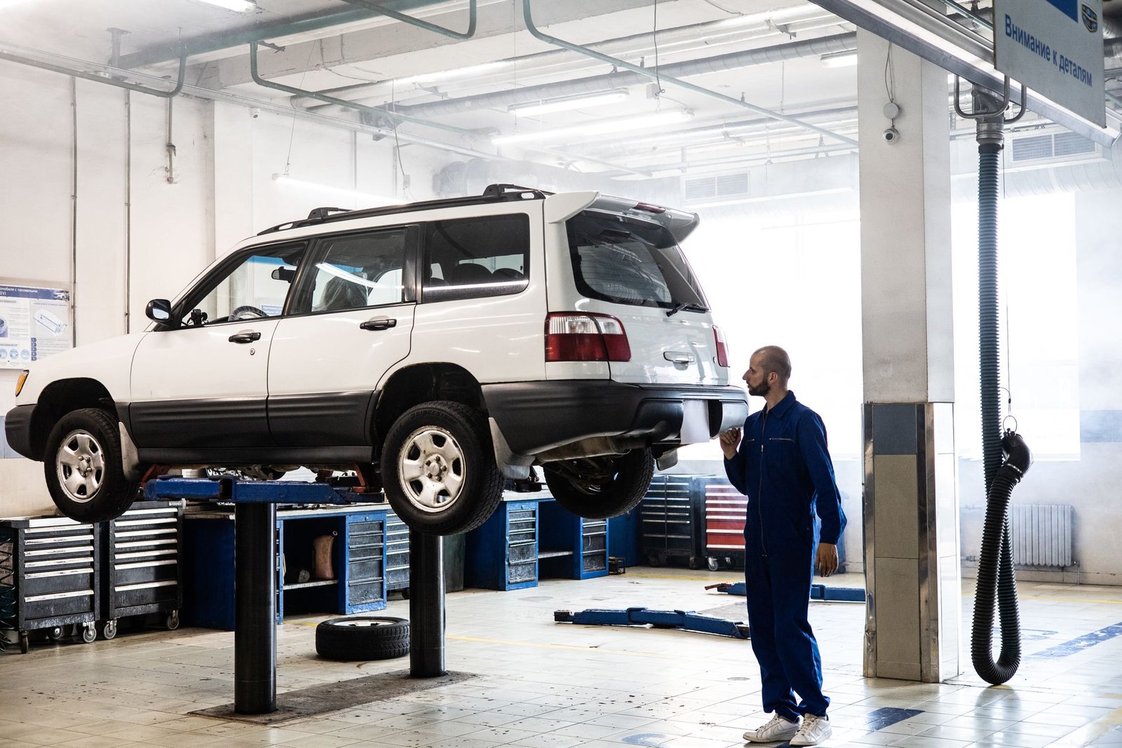 Inspector in blue coveralls checking the condition of a white car