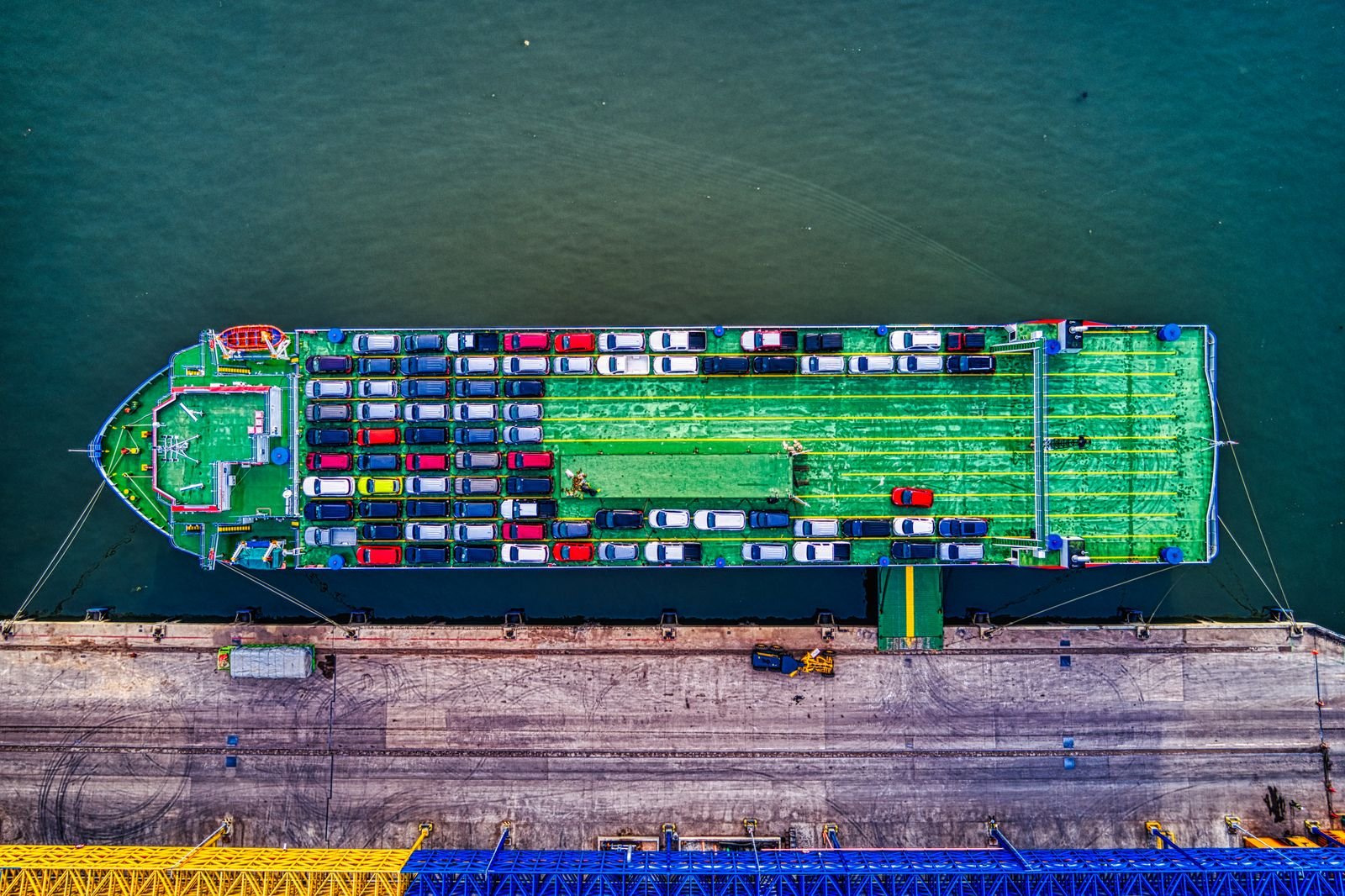 Aerial view of a RoRo car carrier ship loaded with rows of vehicles, docked at a port