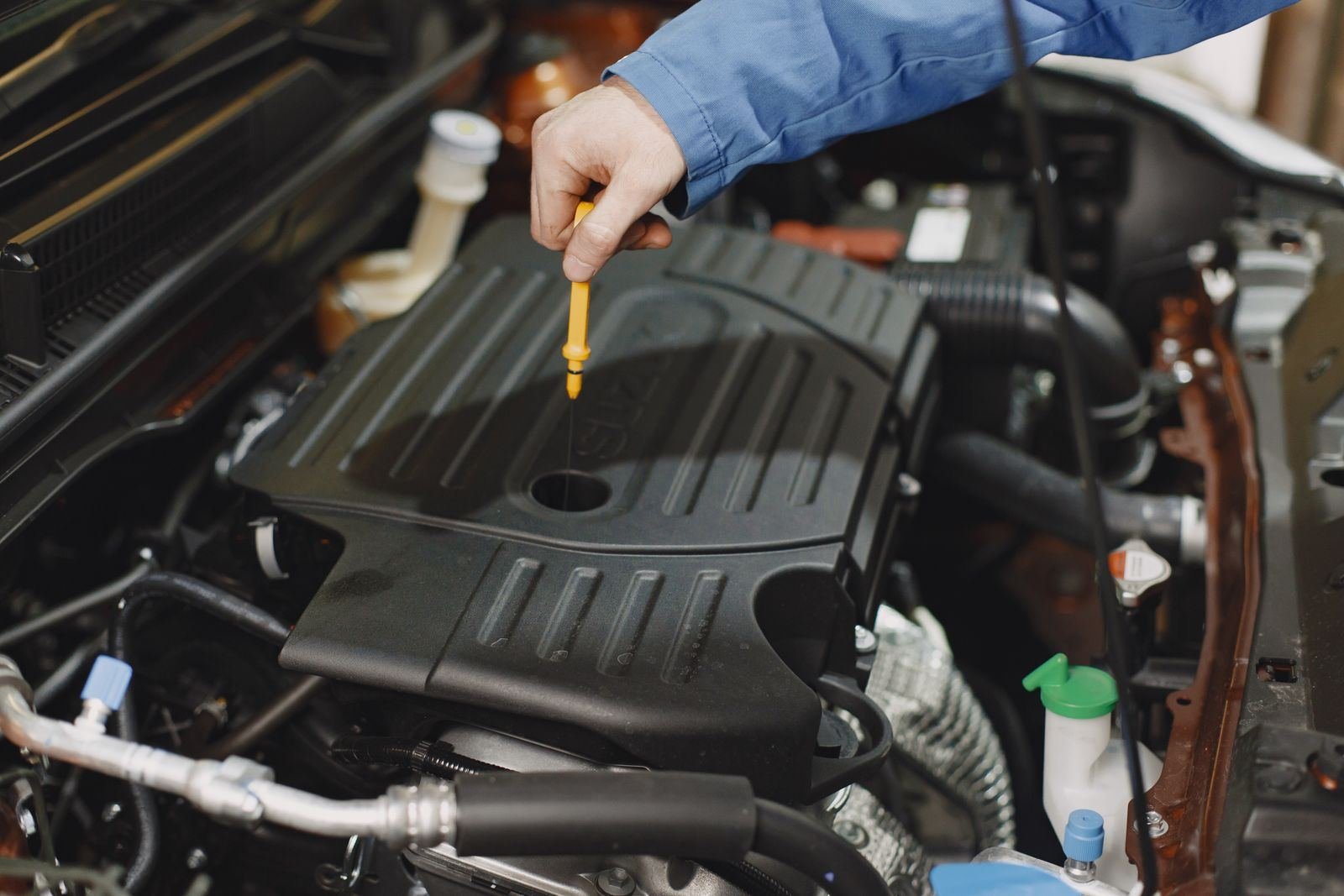 Mechanic checking a car engine oil level with the dipstick