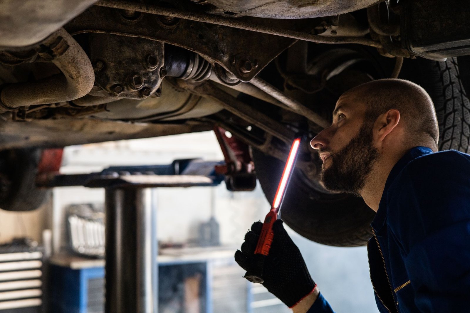 Mechanic inspecting the underside of a car with a work light