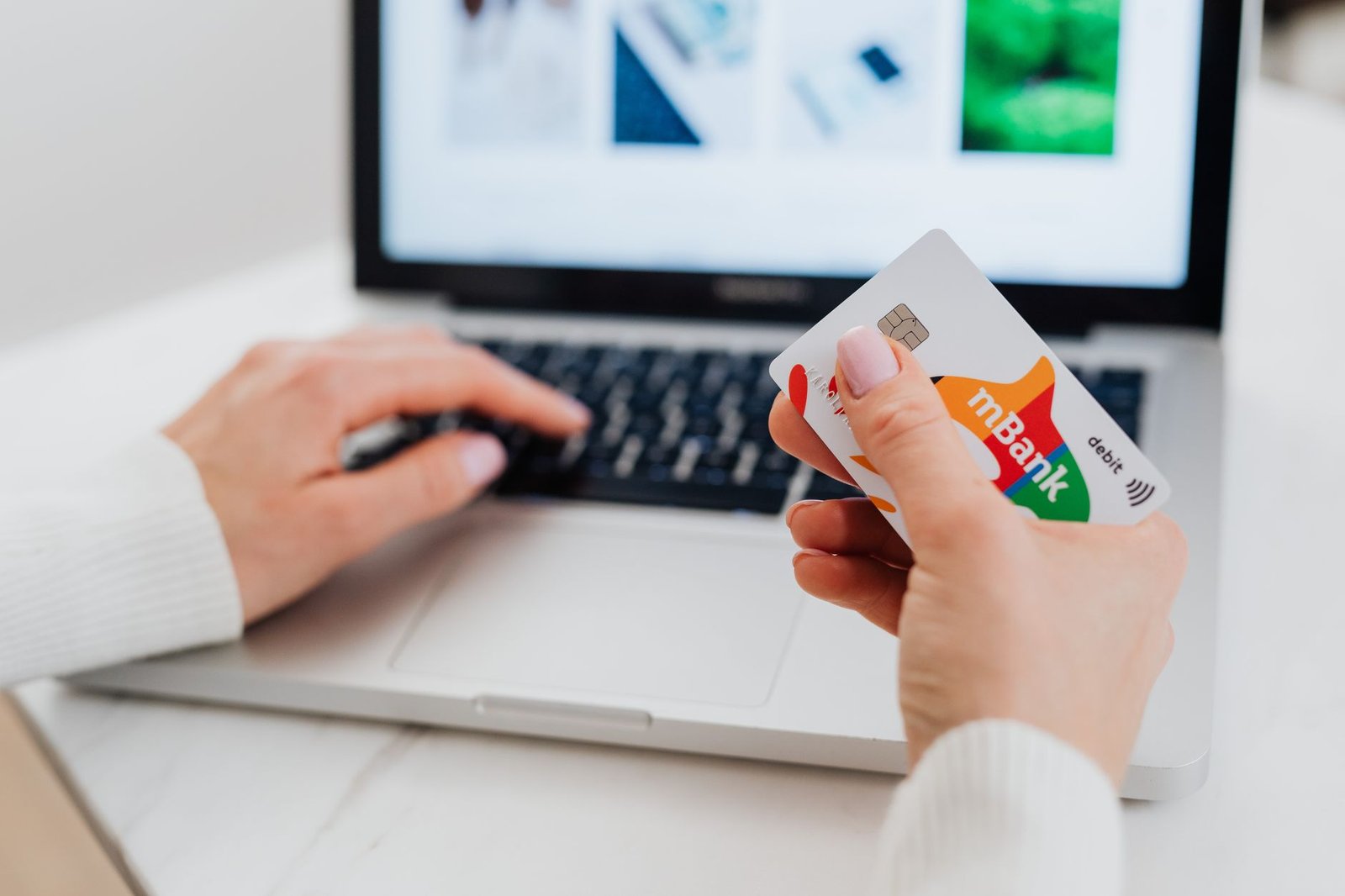 Person holding a bank card while making an online payment on a laptop