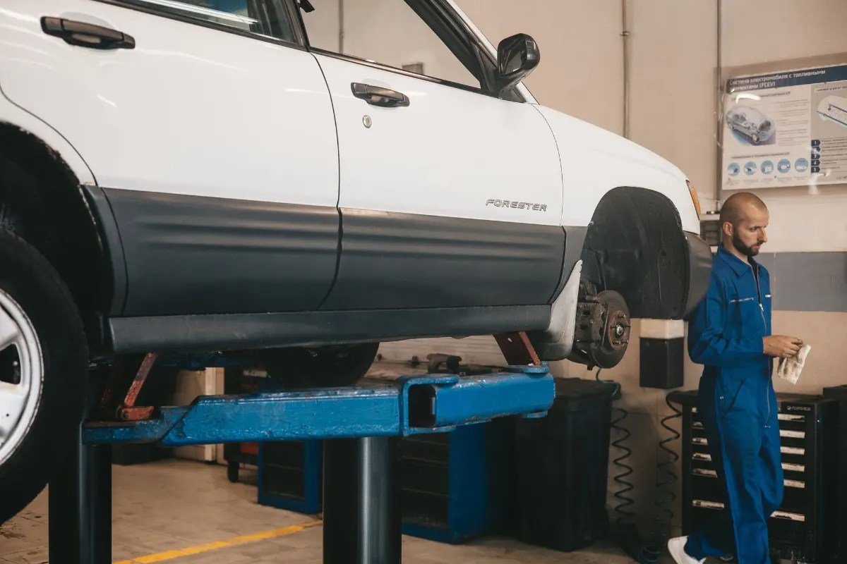 Mechanic inspecting a used SUV raised on a lift during a first service